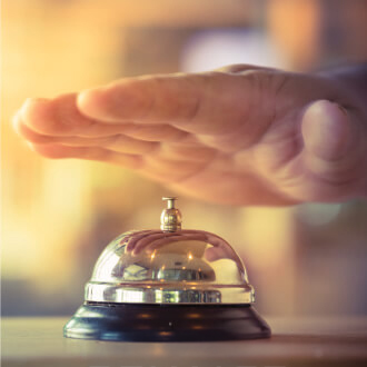 Hand hovering over a service bell on desk