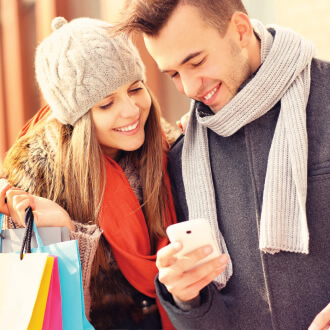 Couple with shopping bags looking at smartphone