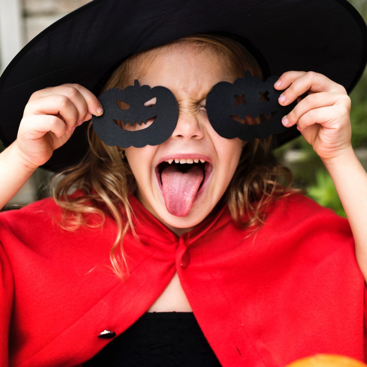 Child in costume with Halloween pumpkin glasses