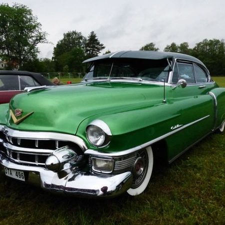 Vintage green Cadillac at outdoor car show.