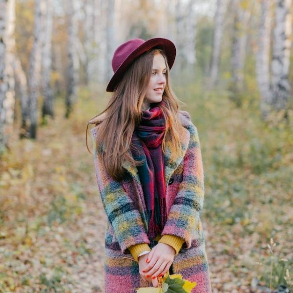 Woman in autumn forest with colorful scarf and hat.